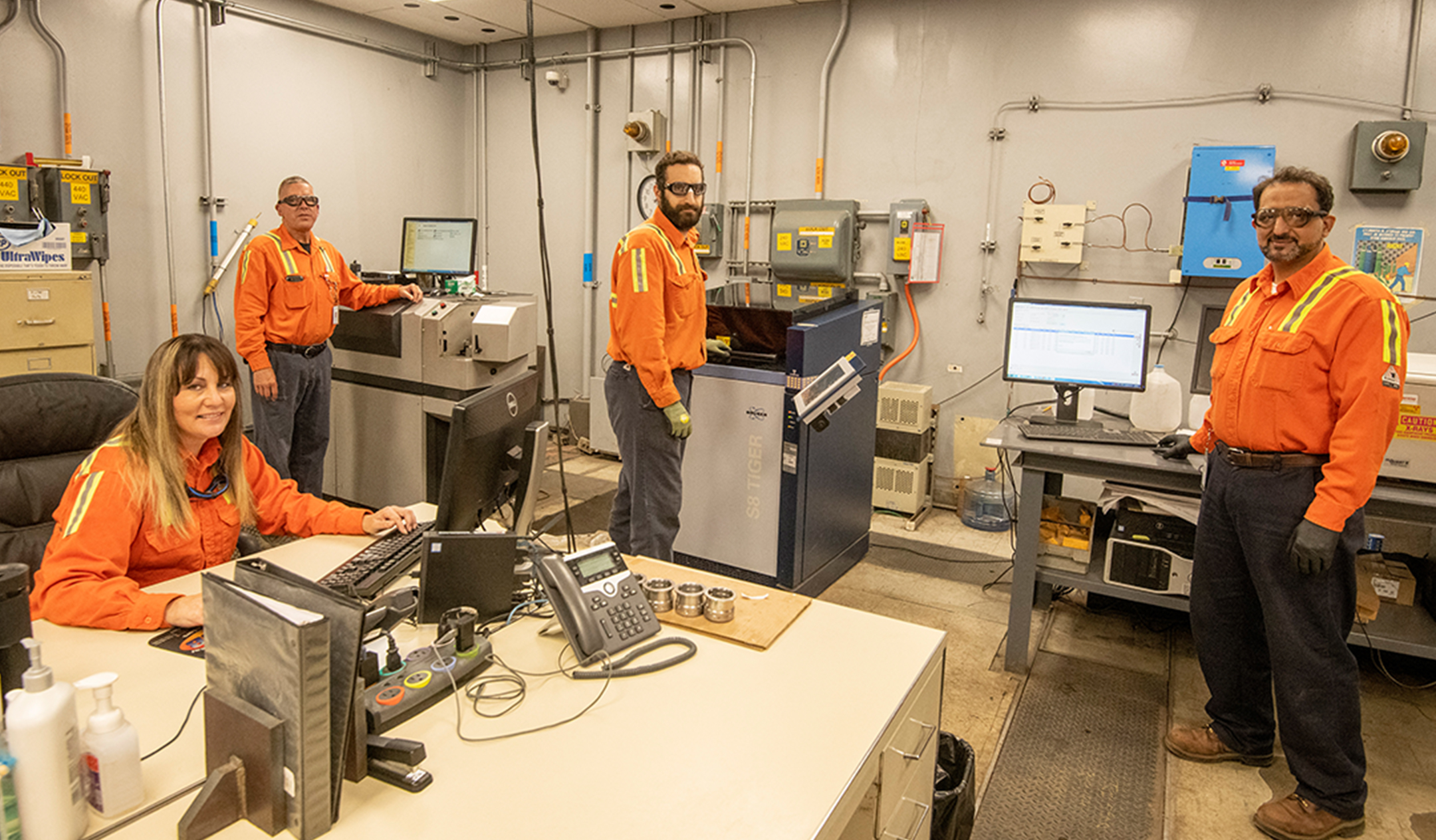 A group of employees pause their work on various computer systems to smile